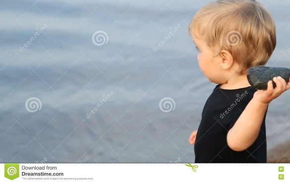 la-blonde-gaie-d-enfant-de-garçon-jette-une-grande-pierre-dans-l-eau-74972652